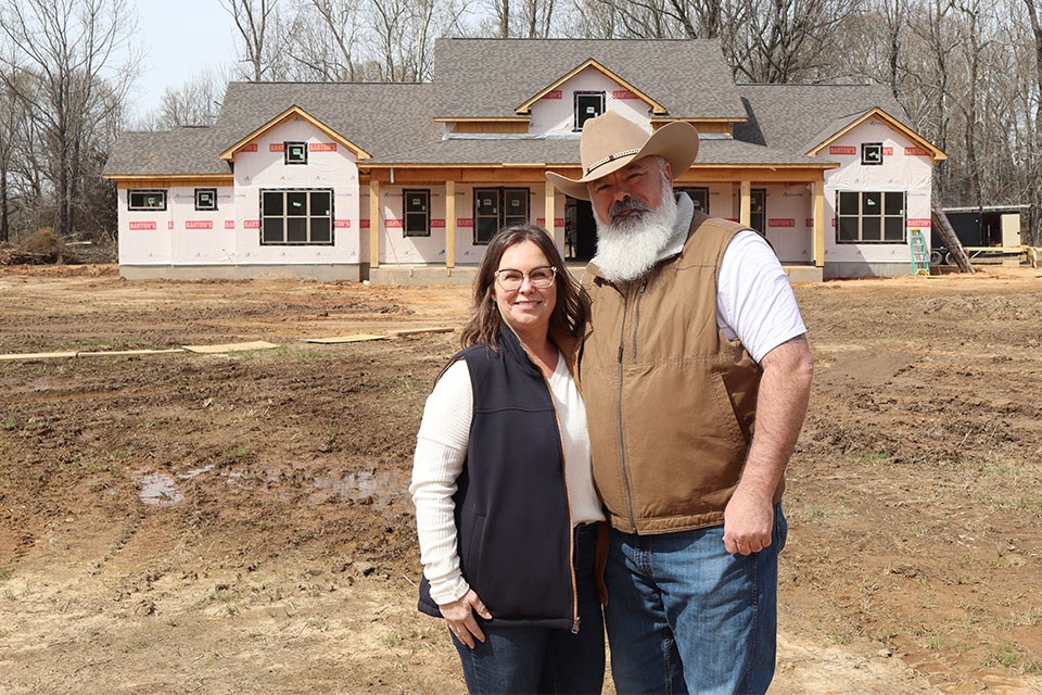 Customers stand in front of rural home construction site financed by Rural 1st