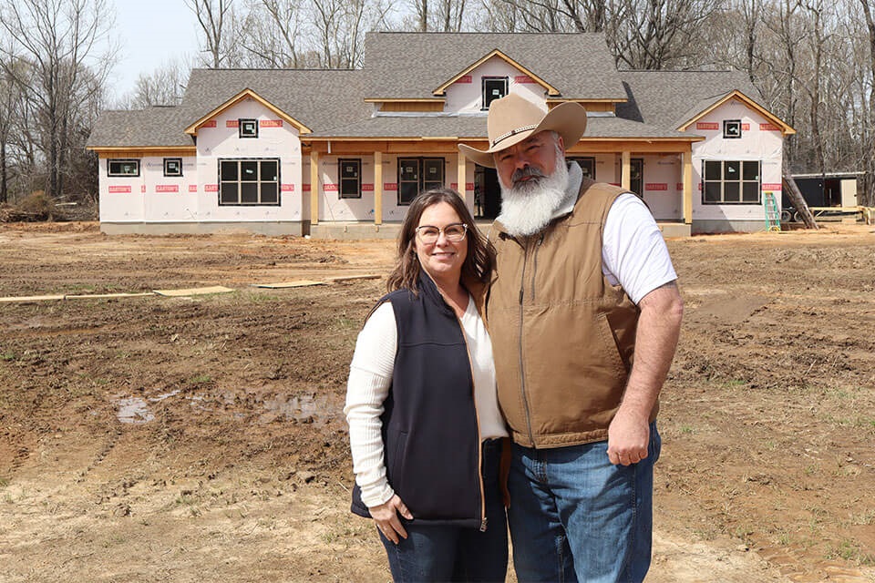 Customers stand in front of rural home construction site financed by Rural 1st.