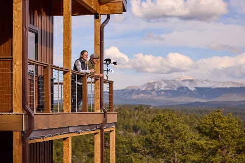 Rural 1st customers stand on porch with scenic Colorado mountains behind them.