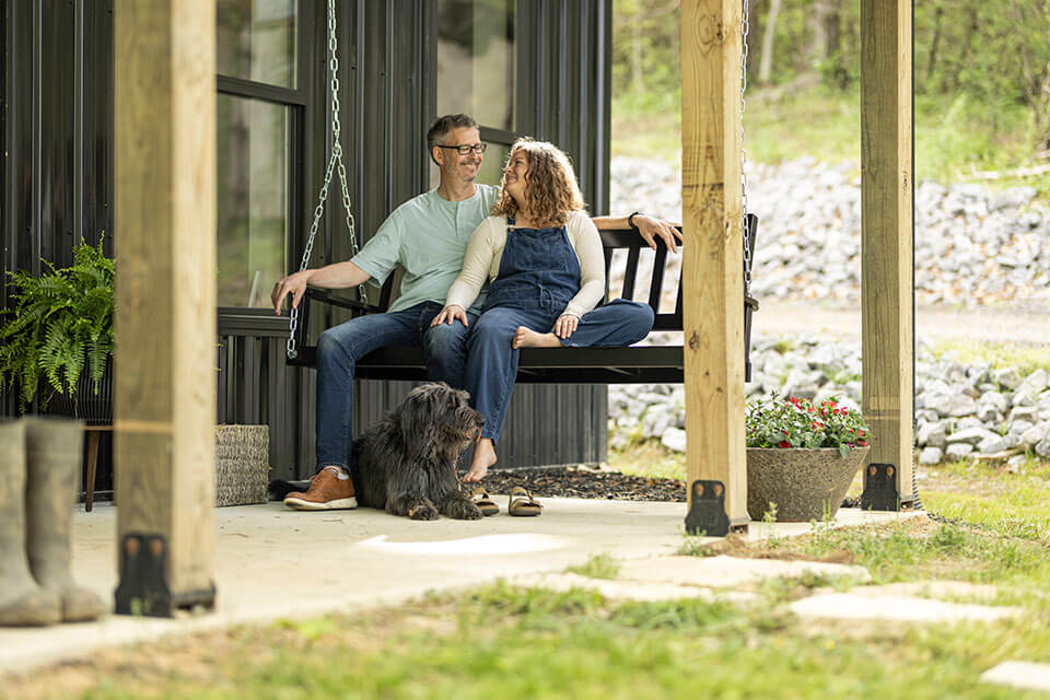 Rural1st_2026_XXXX_Website_StoryBodyImage2_Wohelski_FINAL Couple sitting on porch of barndo financed by Rural 1st.