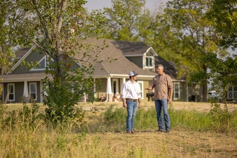 Man talking to loan officer in front of a finished home