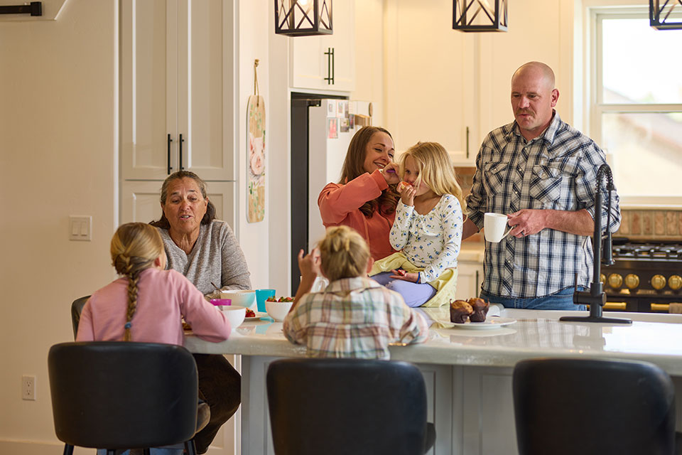 A family happily gathers and interacts around a spacious modern kitchen island.