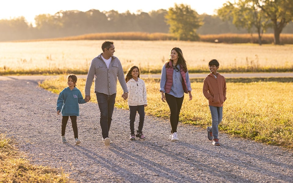 A family of five walking down a rural gravel driveway.