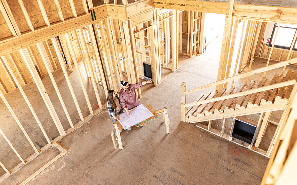 A couple admiring the building plans for their rural home during early stages of construction.