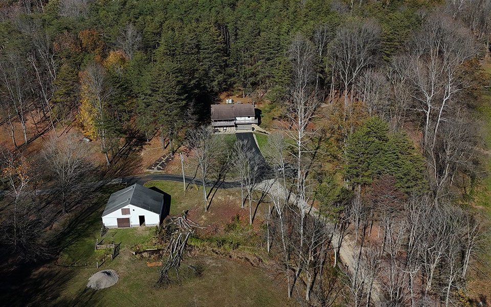 Aerial view of a rural home on a wooded lot.