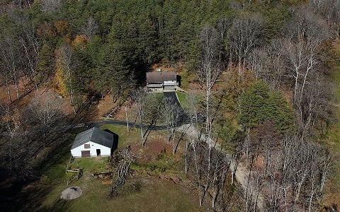 Aerial view of a rural home on a wooded lot.