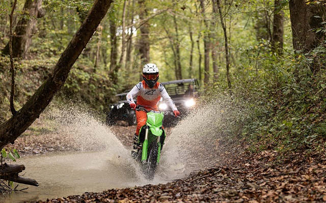 A young man driving a motorbike through a ravine on his rural property.