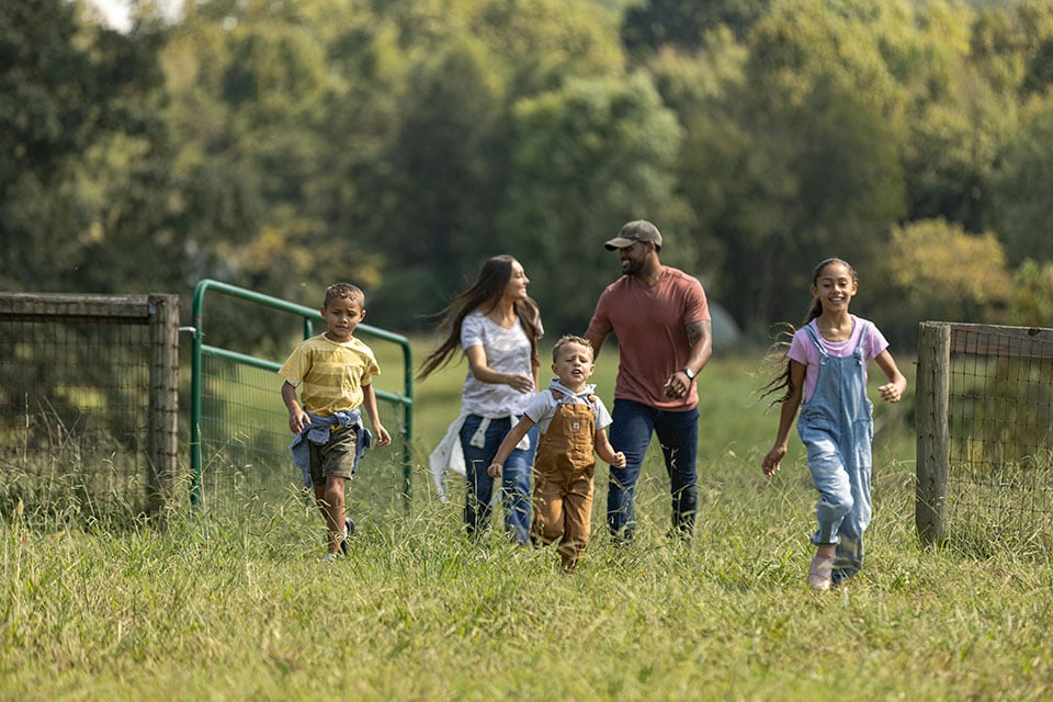 A family walks happily through a field of tall grass.