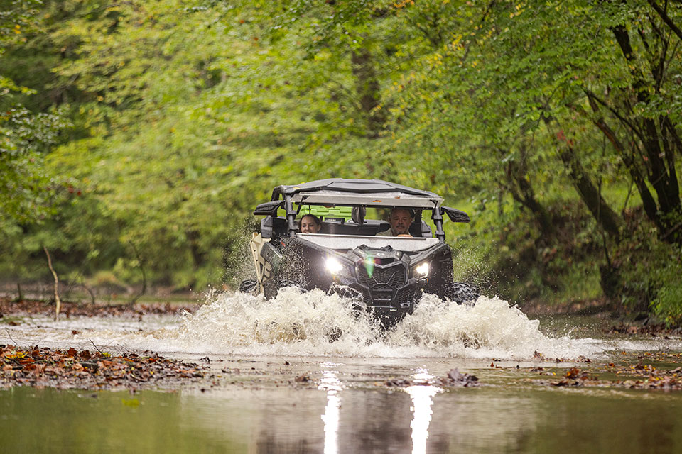 Driving an ATV through a creek in the woods.